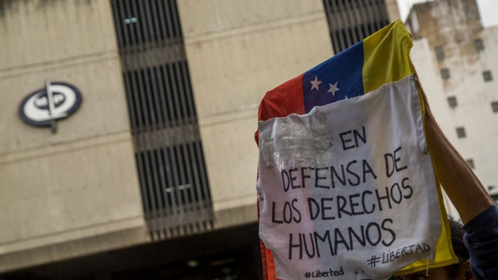 Manifestantes alzan una pancarta en defensa de los DDHH ante la sede del MP, una de las instancias de la justicia venezolana