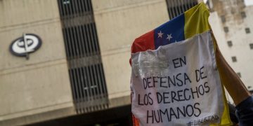 Manifestantes alzan una pancarta en defensa de los DDHH ante la sede del MP, una de las instancias de la justicia venezolana